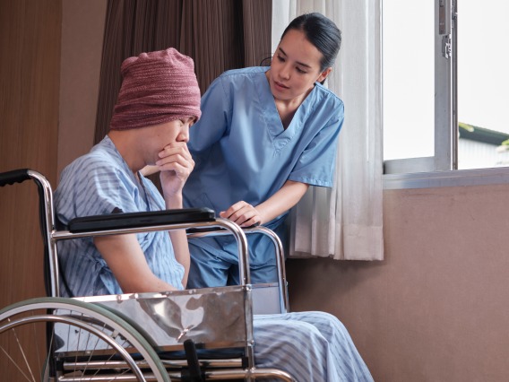 male cancer patient in wheel chair with female nurse standing nearby