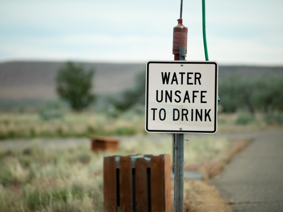 sign on side of road reads "water unsafe to drink"