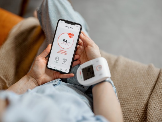 person holding phone while wearing digital blood pressure monitor